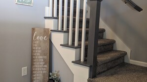 A staircase with a wooden handrail and carpeted steps. - Charming 2-bedroom country house near South Bend and Potato Creek with WiFi, AC. (Bremen)