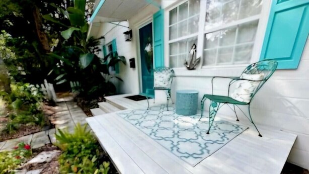 A wooden deck with two green metal chairs and a small table. - Cottage jewel -pet friendly (St. Augustine)