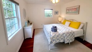 A bedroom with a bed, a window, a radiator, a ceiling fan, and a small table. - Cottage jewel -pet friendly (St. Augustine)