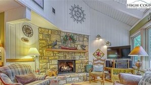 Una sala de estar acogedora con chimenea de piedra, asientos cómodos y un televisor.