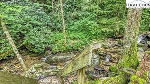 Un puente de madera en un área boscosa con un letrero que dice 'HIGH COUN'.