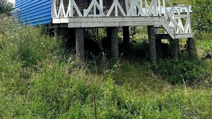 A rustic wooden structure with a blue roof, elevated on stilts, featuring a balcony with white railings.