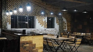 A restaurant interior with a rustic design, featuring exposed brick walls, wooden tables and chairs, and pendant lighting.