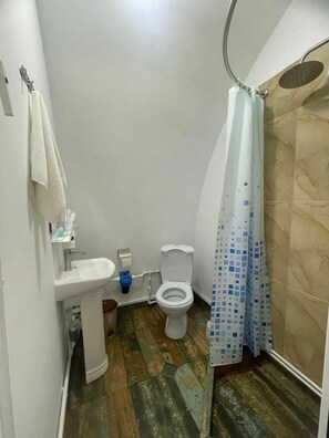 Un baño pequeño con lavamanos, inodoro y cortina de ducha blancos.