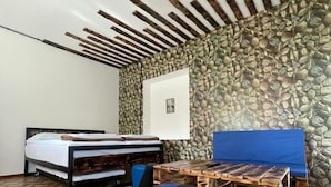 A room with a bed, a wooden table, and a stone wall.