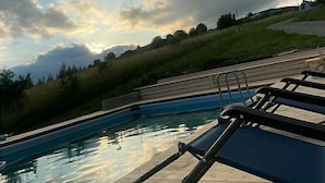 A pool area with lounge chairs and a view of the surrounding landscape.