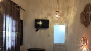 A hotel room with a bed, a TV mounted on the wall, a ceiling fan, and a window with curtains. - Hôtel Ayachi (Tunis)