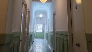 A hallway with a high ceiling, a central light fixture, and doors on both sides. - Hôtel Ayachi (Tunis)