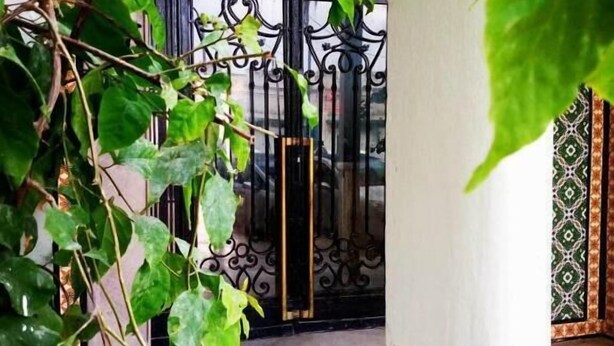 A view of a tiled courtyard with a wrought iron gate and a column. - Hôtel Ayachi (Tunis)