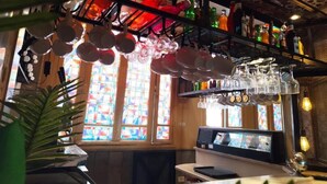 A bar area with hanging glassware, a computer monitor, and a plant. - Hôtel Ayachi (Tunis)