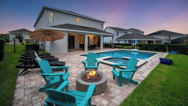 A backyard with a pool, fire pit, and outdoor seating.