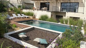 A modern outdoor pool area with lounge chairs, a pergola, and a staircase leading to a covered deck. - Villa l'Annexe between Avignon and Nîmes: outdoor swimming pool, gym,... (Rochefort-du-Gard)