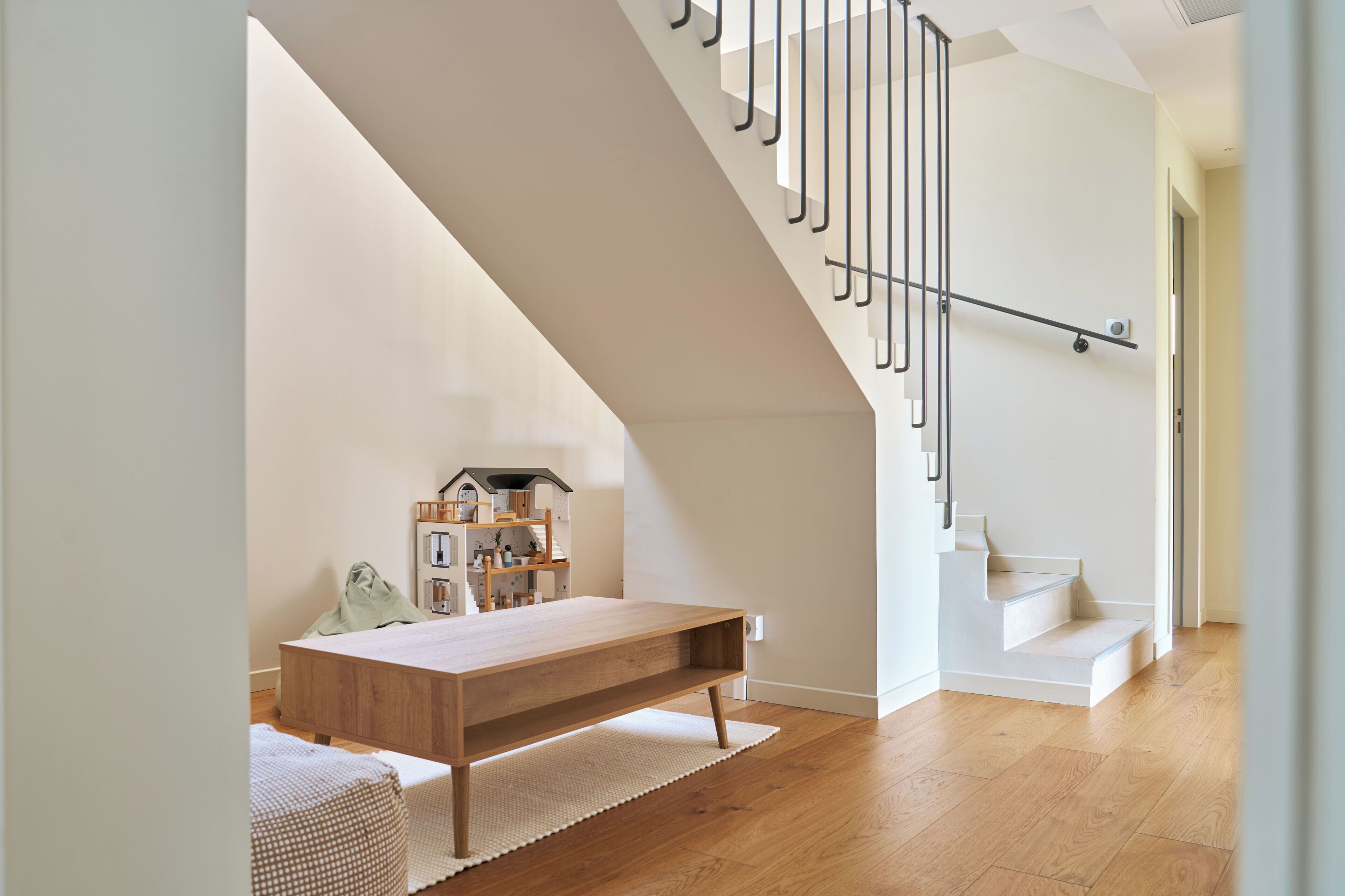 Un interior moderno con una mesa de madera, una escalera y una estantería.