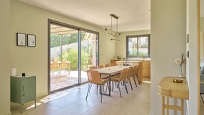 A modern kitchen with a dining area, large windows, and a sliding glass door leading to a patio. - Villa l'Annexe between Avignon and Nîmes: outdoor swimming pool, gym,... (Rochefort-du-Gard)