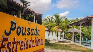 A sign for Pousada Estrela da Manhã with a clear view of the surrounding area including a pool and lounge chairs. - Pousada Estrela da manhã (Barreirinhas)