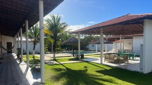A covered outdoor area with a swimming pool, lounge chairs, and a grassy lawn. - Pousada Estrela da manhã (Barreirinhas)