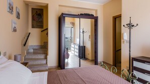 A bedroom with a bed, a wardrobe, a mirror, and a staircase leading to another room. - Naxos Bay View With Terrace by Wonderful Italy (Giardini Naxos)