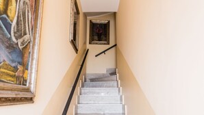 A marble staircase with a handrail, leading to a landing with a framed artwork. - Naxos Bay View With Terrace by Wonderful Italy (Giardini Naxos)