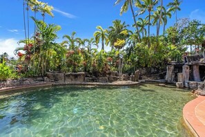 A clear pool surrounded by tropical vegetation and a rocky landscape.