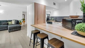 Una cocina moderna con encimera de madera, taburetes de bar y horno empotrado.