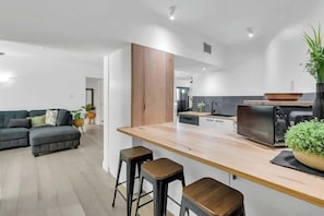 Une cuisine moderne avec un plan de travail en bois, des tabourets de bar et un four encastré.