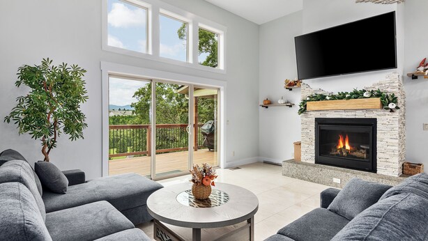 Ein modernes Wohnzimmer mit grauen Sofas, einem runden Couchtisch, einem Kamin und einem an der Wand befestigten Fernseher.