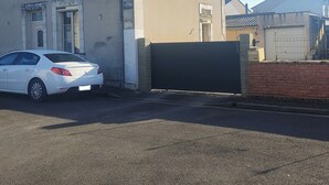 A building with a beige facade, a white car parked in front, and a closed gate. - Cosy dwelling in the village center (Aubigné-Racan)