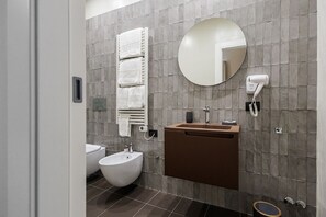 A modern bathroom with a bidet, a sink with a mirror, and a towel rack.