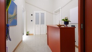 A hallway with a reception desk, a door with frosted glass panels, and a small potted plant. - RV 2.0  (Messina)