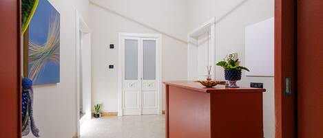 A hallway with a reception desk, a door with frosted glass panels, and a small potted plant.