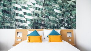 A hotel room with a bed, two pillows, a headboard, and a wall with a forest pattern. - Sweet Home By Novotel Bordeaux Mérignac (Mérignac)
