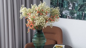 A modern hotel room with a round table, a green vase with flowers, a brown chair, and a large forest-themed wall mural. - Sweet Home By Novotel Bordeaux Mérignac (Mérignac)