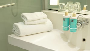 A bathroom with a white sink, two rolled towels, and two bottles of liquid soap. - Sweet Home By Novotel Bordeaux Mérignac (Mérignac)