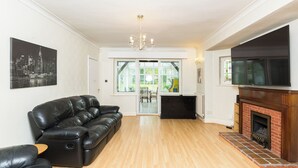 A living room with a black leather sofa, a fireplace, and a television. - 6 bedroom house near Edgbaston Stadium (Birmingham)