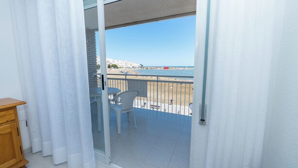 A balcony with a view of the beach and a dining area with a table and chairs. - Forner Apartamentos Peñiscola (Peniscola)