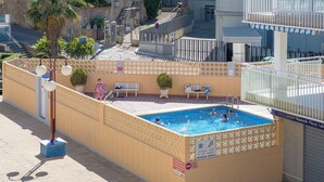 A swimming pool with a tiled deck, a bench, and a potted plant. - Forner Apartamentos Peñiscola (Peniscola)
