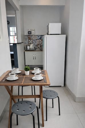 Una cocina compacta con un refrigerador blanco, un mueble pequeño y salpicadero de azulejos.