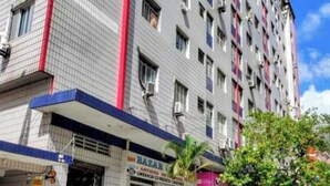 Un edificio a più piani con facciata piastrellata, condizionatori d'aria e un negozio con insegna 'BAZAR' al piano terra.