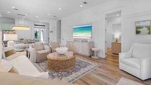 A spacious living room with a large TV, comfortable seating, and a view of the kitchen. - Sea La Vie - 30A! Summers Edge in Seagrove Beach, Heated Community Pool! (Seagrove Beach)
