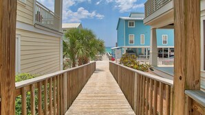 A wooden boardwalk leading to a beachfront property with multiple-story buildings, a clear sky, and a view of the ocean. - Sea La Vie - 30A! Summers Edge in Seagrove Beach, Heated Community Pool! (Seagrove Beach)