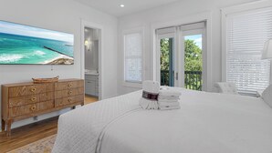 A bedroom with a large bed, a wooden dresser, a painting of a beach, and a view of greenery through the window. - Sea La Vie - 30A! Summers Edge in Seagrove Beach, Heated Community Pool! (Seagrove Beach)
