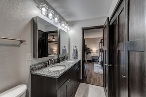 Un baño moderno con tocador doble lavamanos, un espejo grande y una ducha a ras de suelo.