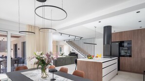 A modern kitchen with a central island, wooden cabinets, and a black refrigerator. - Villa Prima Lux (Kastela)