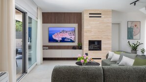 A modern living room with a flat-screen TV, a fireplace, and a sofa. - Villa Prima Lux (Kastela)
