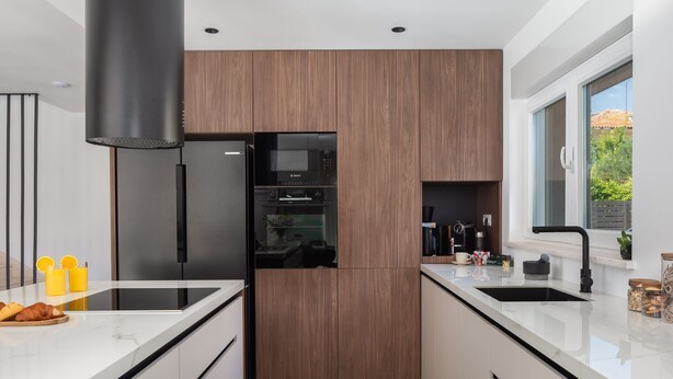 A modern kitchen with a central island, black appliances, and a view of the outdoors. - Villa Prima Lux (Kastela)