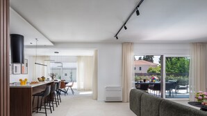 A modern kitchen with a dining area, a large sliding glass door to the outside, and a grey sofa in the living area. - Villa Prima Lux (Kastela)