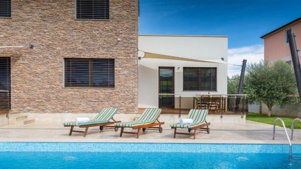 A swimming pool with lounge chairs and a patio area. - Casa Gigi (Medulin)