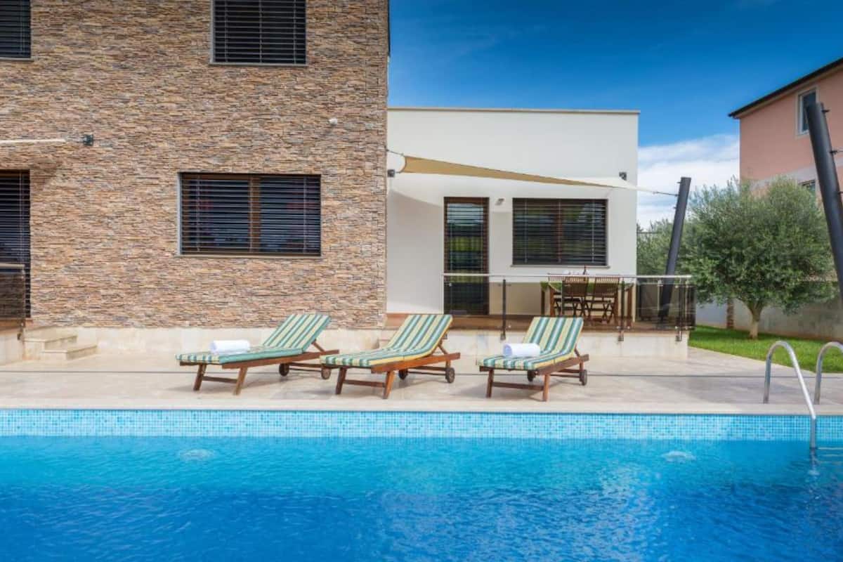 A swimming pool with lounge chairs and a patio area.