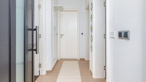 A hallway with white walls, a tiled floor, and doors on both sides. - Casa Gigi (Medulin)