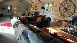 A cozy living room with a sectional sofa, a coffee table, and a stone wall.